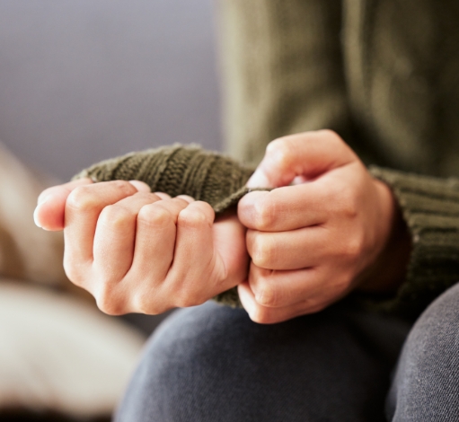 Hand pulling at sleeve of a sweater.