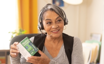 Woman wearing headset holding box of nicotine mini lozanges.