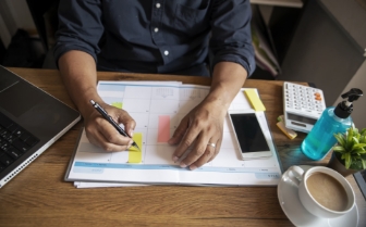 Person writing on desk calendar.